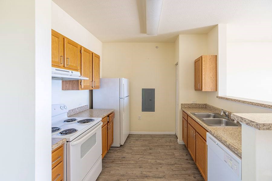 A kitchen with white appliances and wooden cabinets.