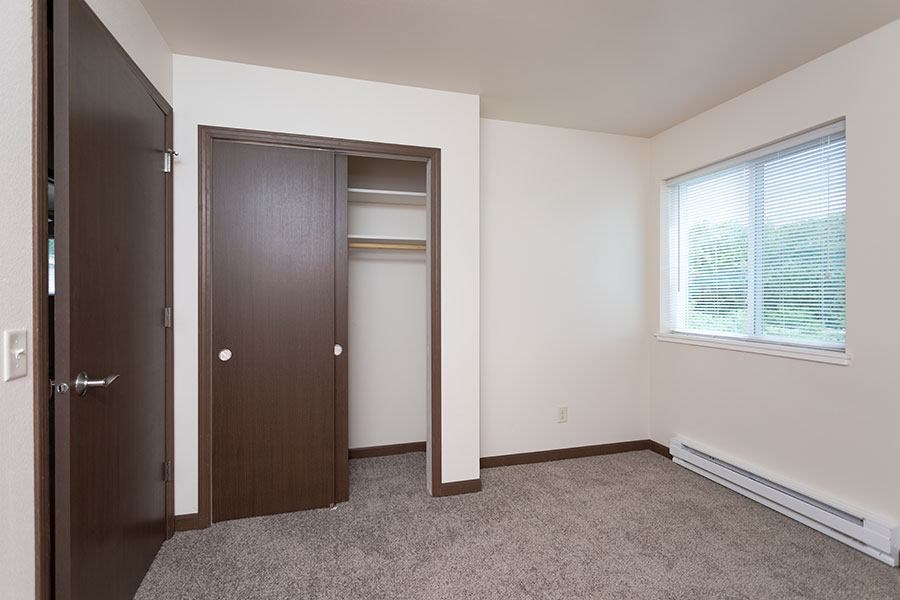 A room with a brown door and a window with blinds.