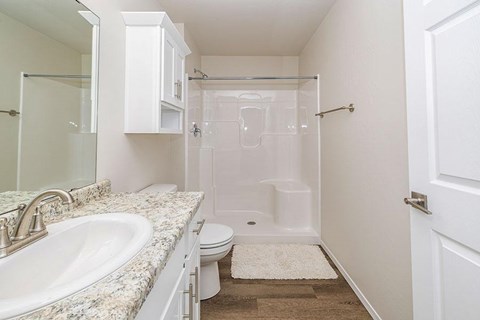 A white bathroom with a sink, toilet, and shower.
