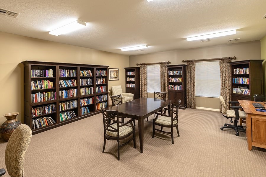 A room with a table, chairs, and a bookshelf filled with books.