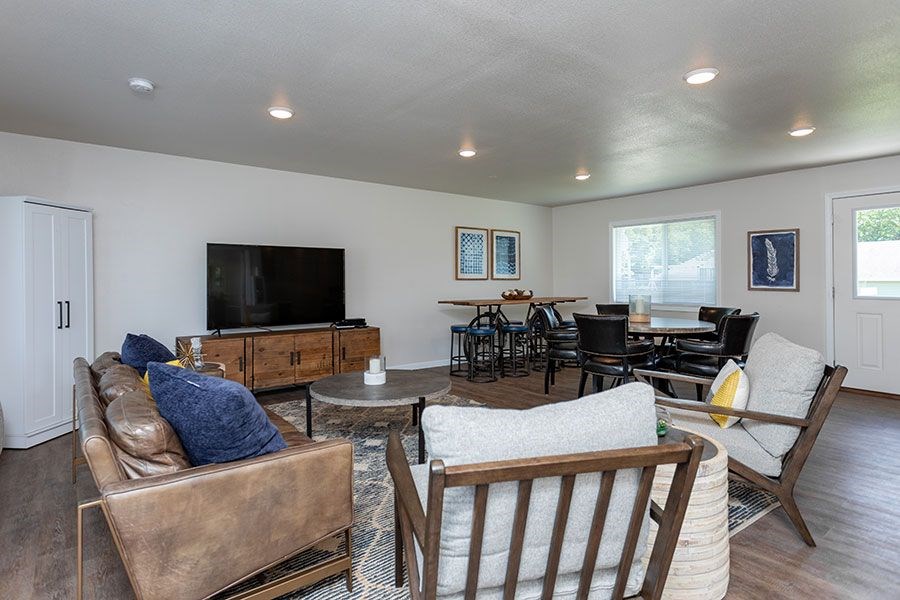 A living room with a brown leather couch and a white chair.