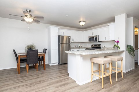 A kitchen with a bar stool and a dining table.