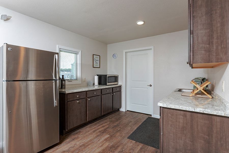 A kitchen with a stainless steel refrigerator and wooden floors.