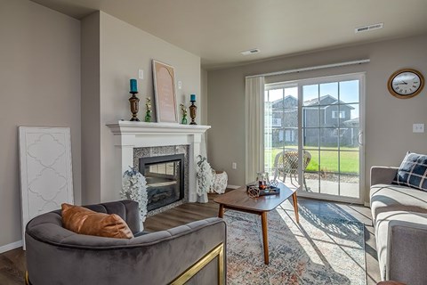 A living room with a grey couch and a fireplace.