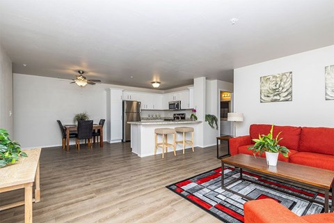 A living room with a red couch and a dining table with chairs.