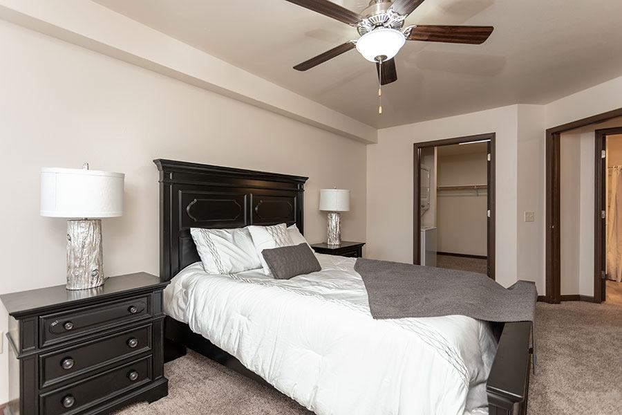 A bedroom with a bed, nightstands, and a ceiling fan.