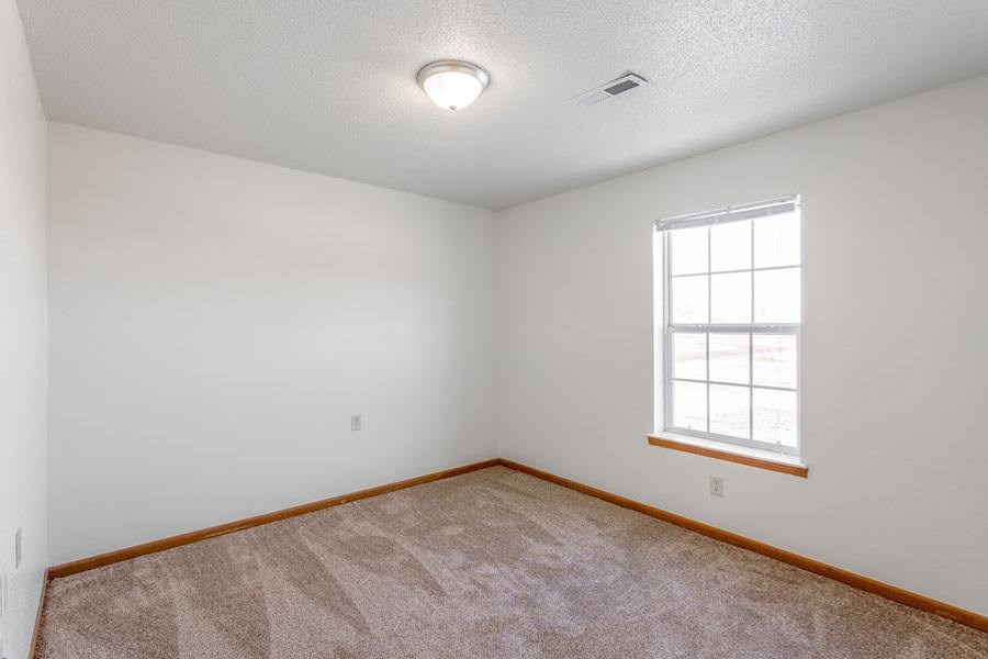 A room with a window and carpeted floor.