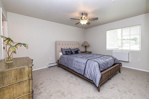 A bedroom with a bed, dresser, and ceiling fan.