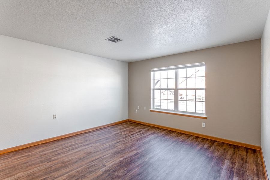 A room with a window and wooden flooring.