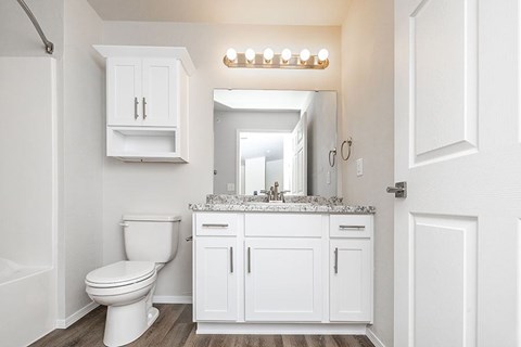 A white bathroom with a toilet, sink, and mirror.