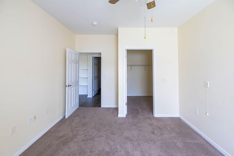 A room with a carpeted floor and a ceiling fan.