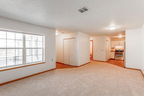 A spacious room with a window, a door, and a kitchenette.