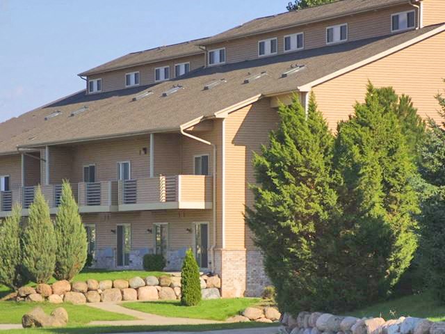 a large yellow house with trees and a lawn