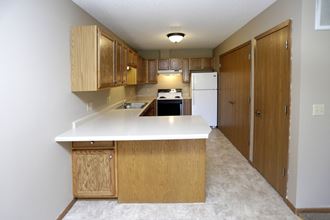 an empty kitchen with wooden cabinets and a white counter top