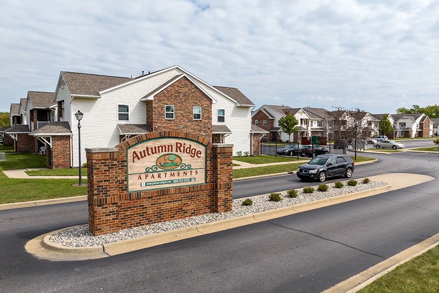 A sign for Autumn Ridge Apartments is in front of a brick house.