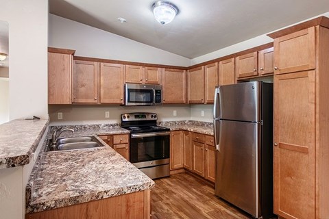 A kitchen with wooden cabinets and granite countertops.