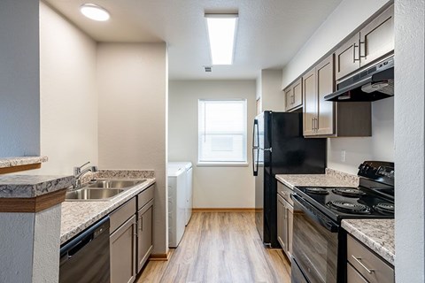 A kitchen with a black fridge and stove top oven.