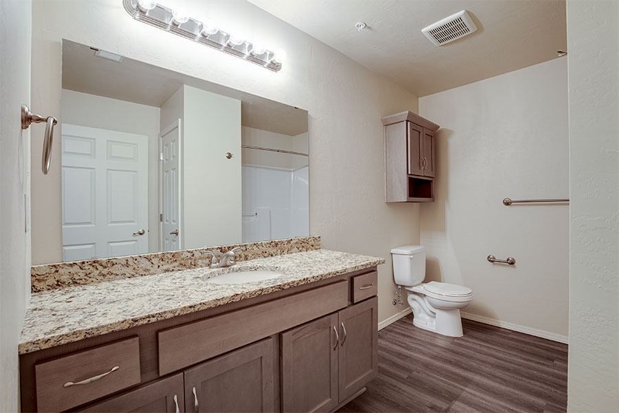 A bathroom with a granite counter top and a white toilet.