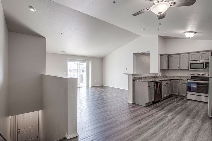 A spacious kitchen and living room with wood flooring and white walls.