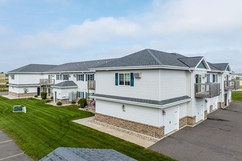 A white house with a grey roof and a green lawn in front.