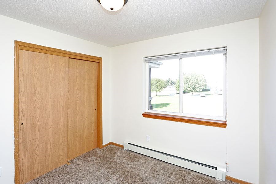 A room with a brown door and a window with a view of the outside.