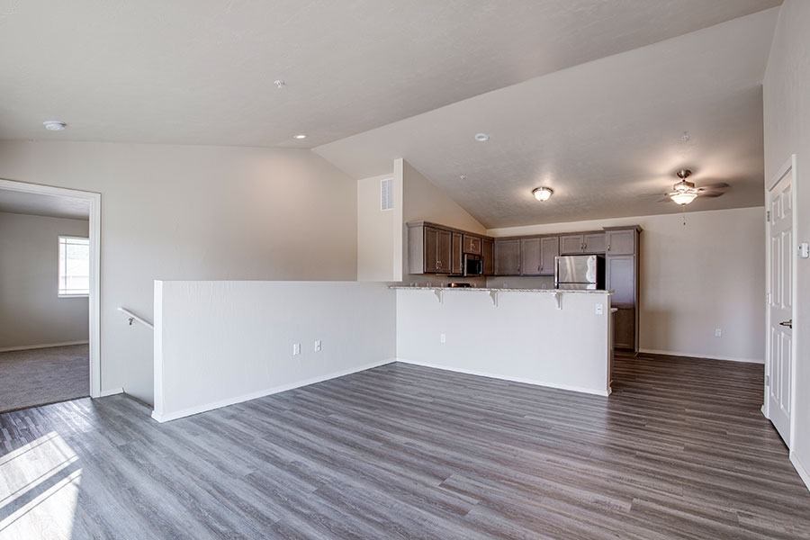 A large, empty room with a kitchen area in the background.