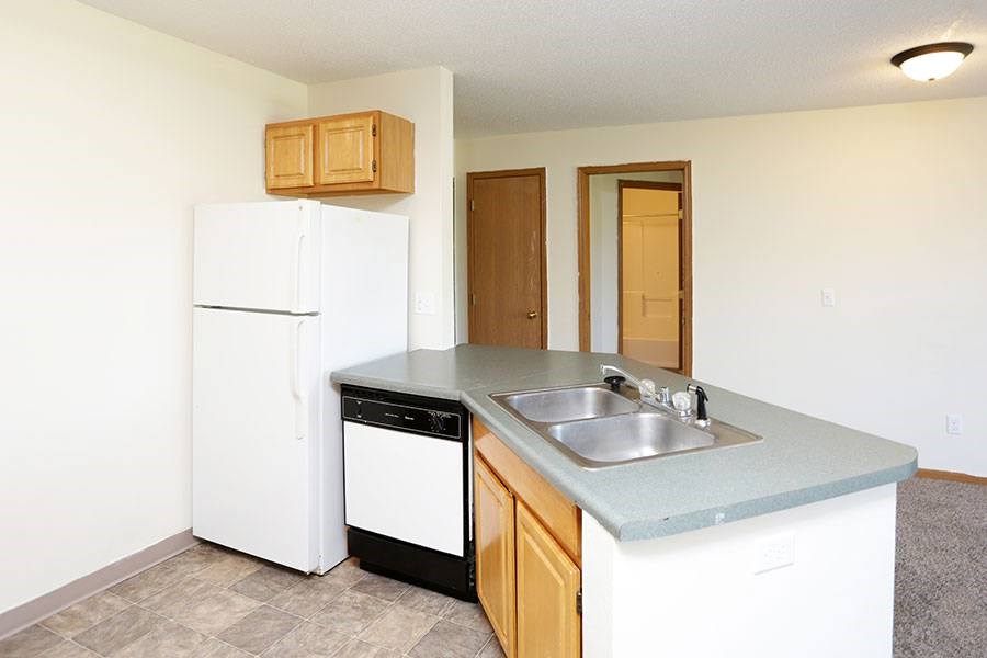 A kitchen with a white fridge, a black dishwasher, and a sink.
