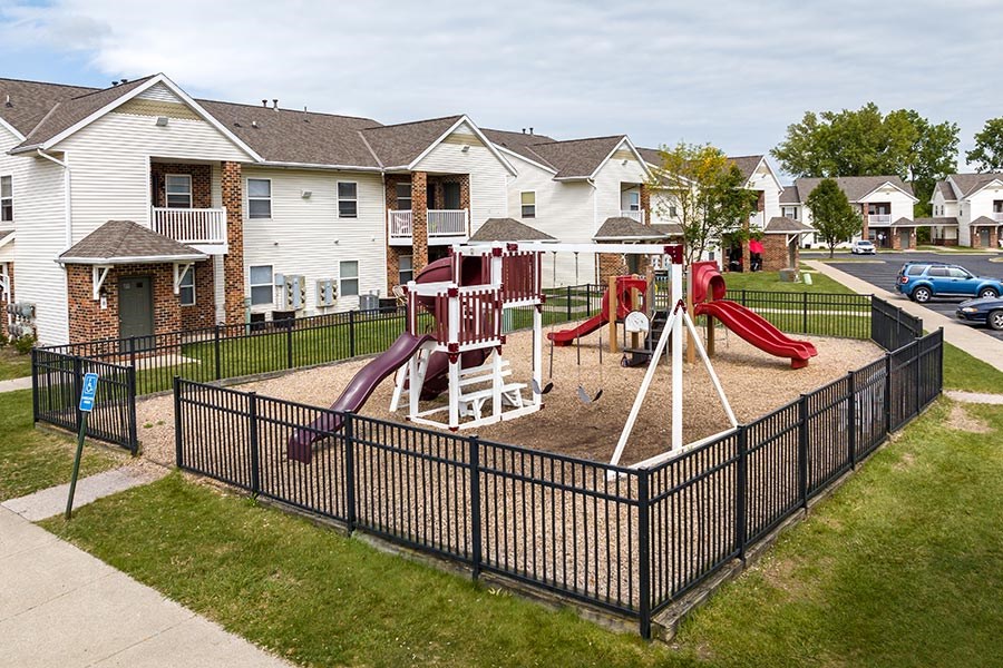 A playground with a red slide and a white sandbox.