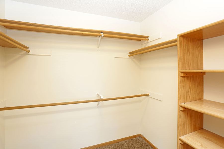 A white room with a shelf and a hanging rail.