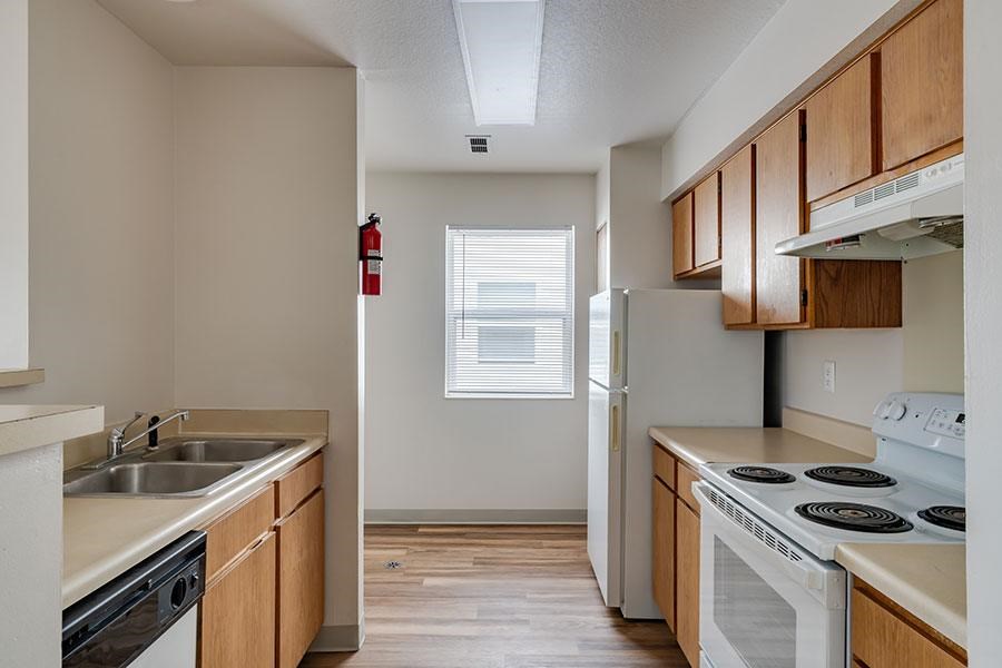 A kitchen with a stove, sink, and cabinets.