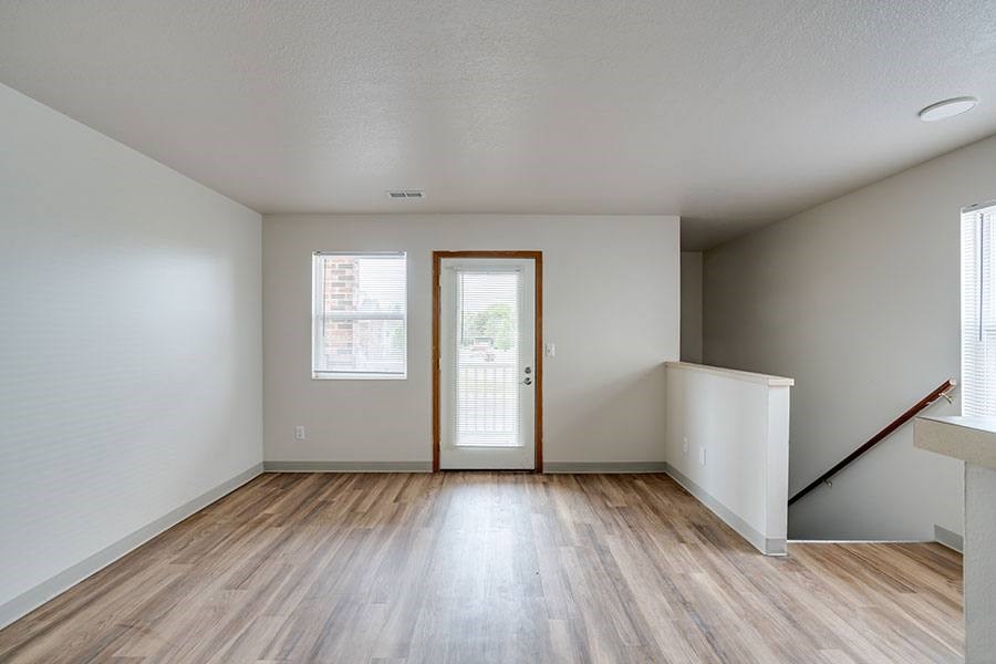 A room with a wooden floor and a door leading to a balcony.