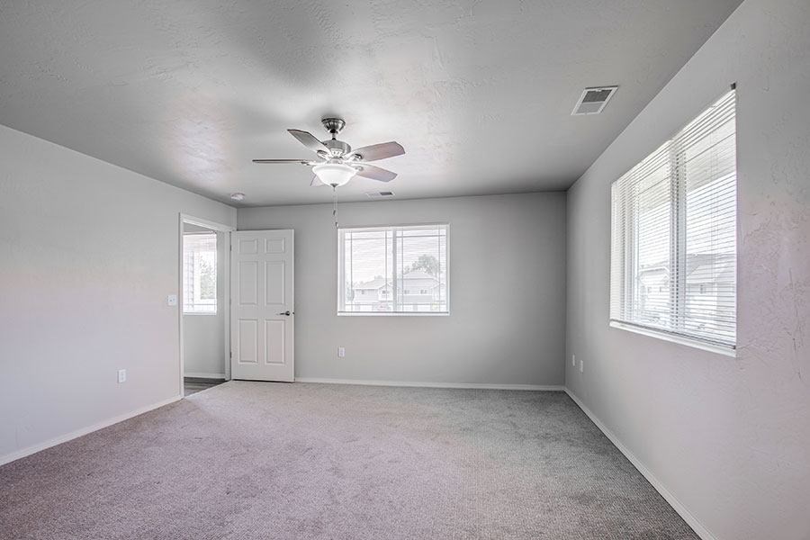 A room with a ceiling fan and carpeted floor.