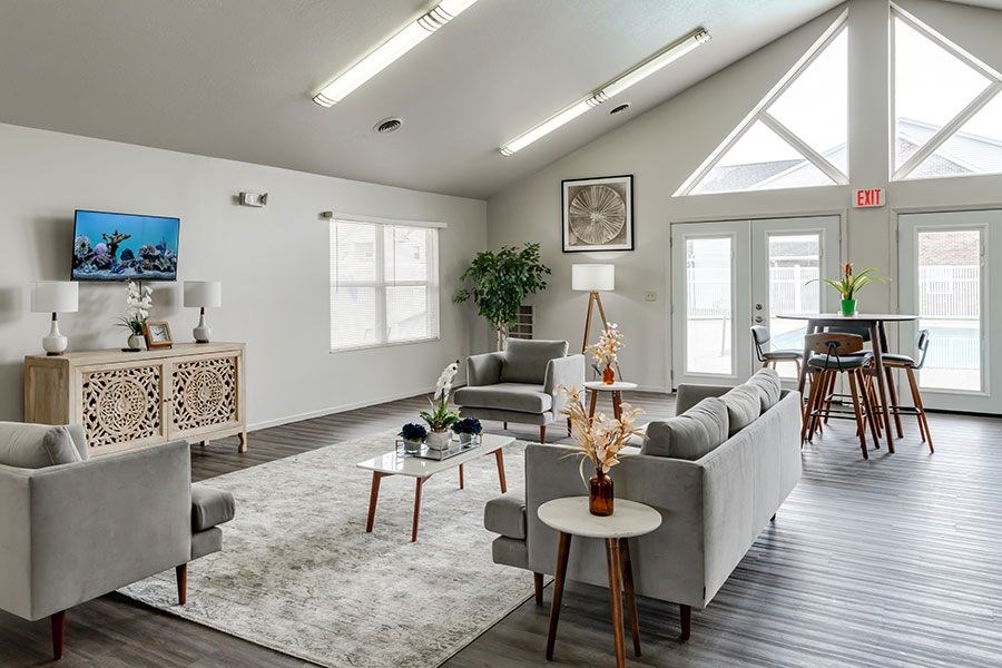 A living room with a grey couch, a coffee table, and a TV on the wall.