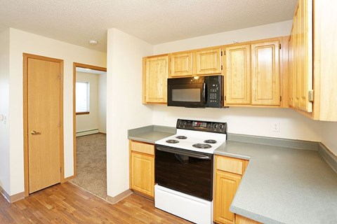 A kitchen with wooden cabinets and a black microwave above the stove.