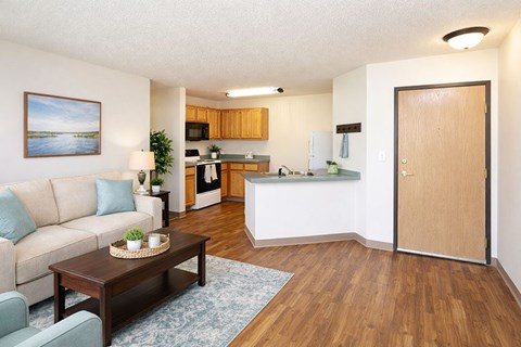 A living room with a couch, coffee table, and a view of the kitchen.