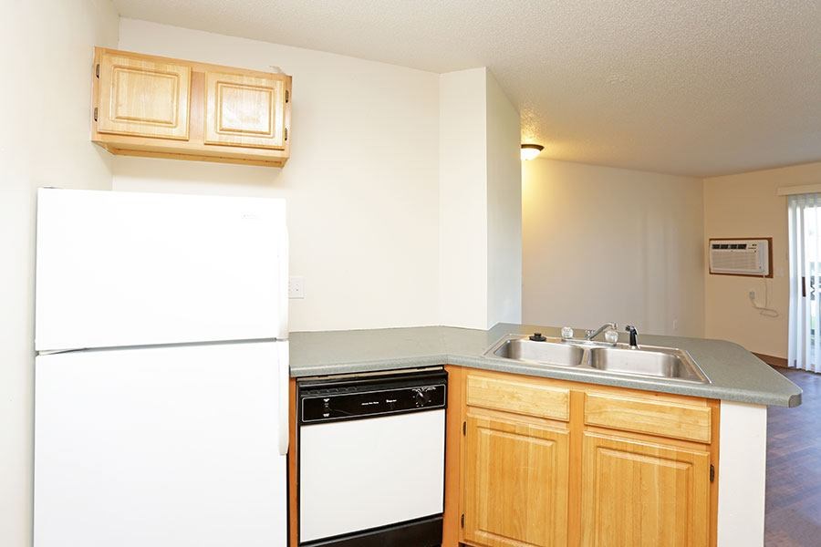 A kitchen with a white refrigerator and wooden cabinets.