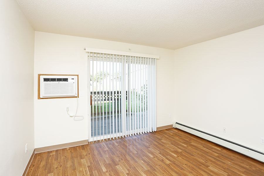 A room with a wooden floor and a window with blinds.