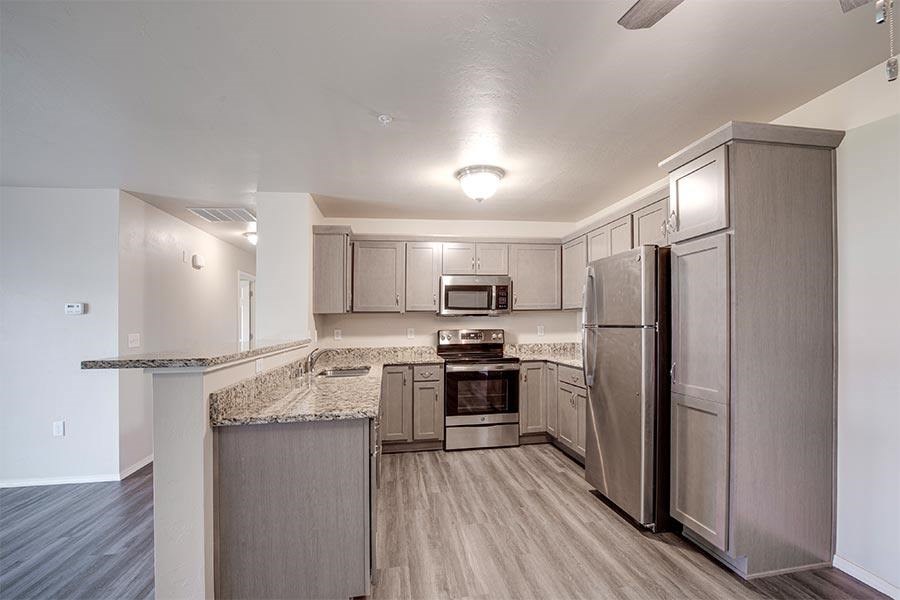 A kitchen with a refrigerator, oven, and microwave.