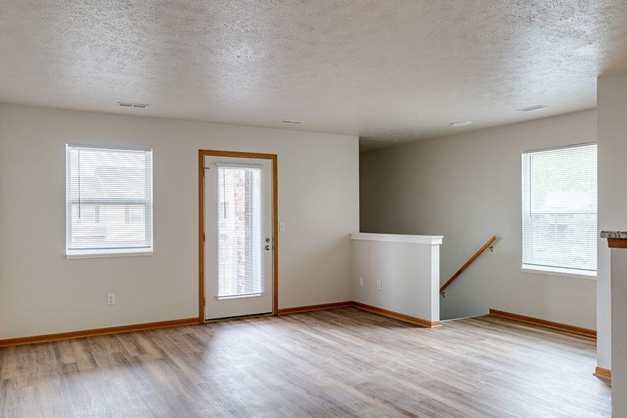 A room with a wooden floor and a window with blinds.