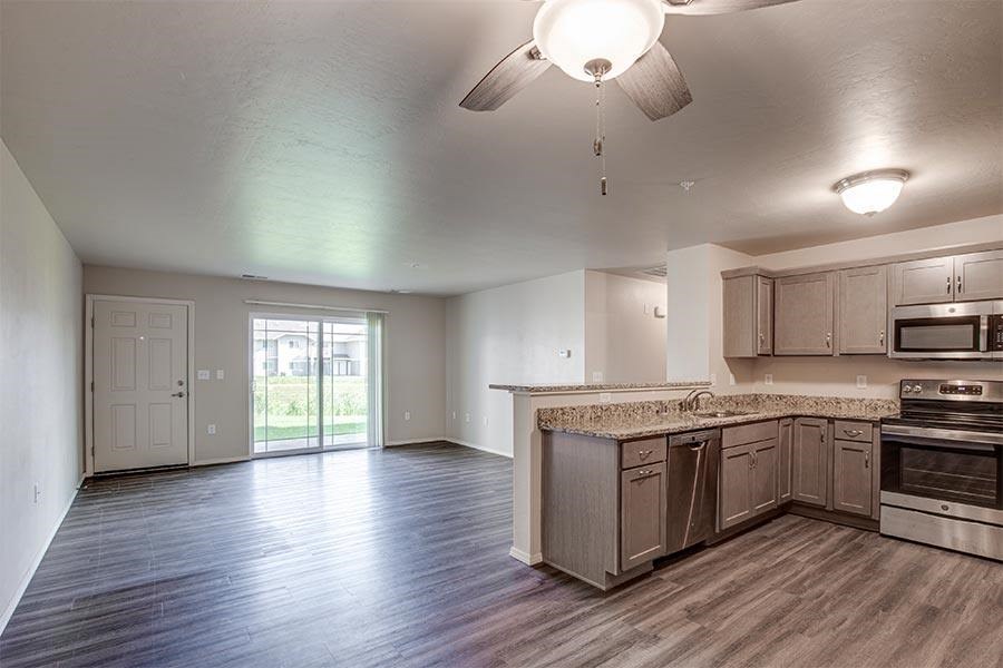 A kitchen with wooden floors and a ceiling fan.