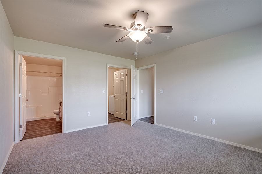 A room with a ceiling fan and carpeted floor.