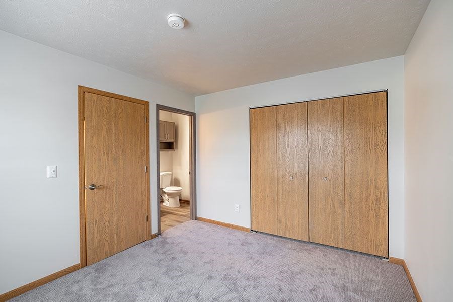A room with a carpeted floor and a toilet visible through the open door.