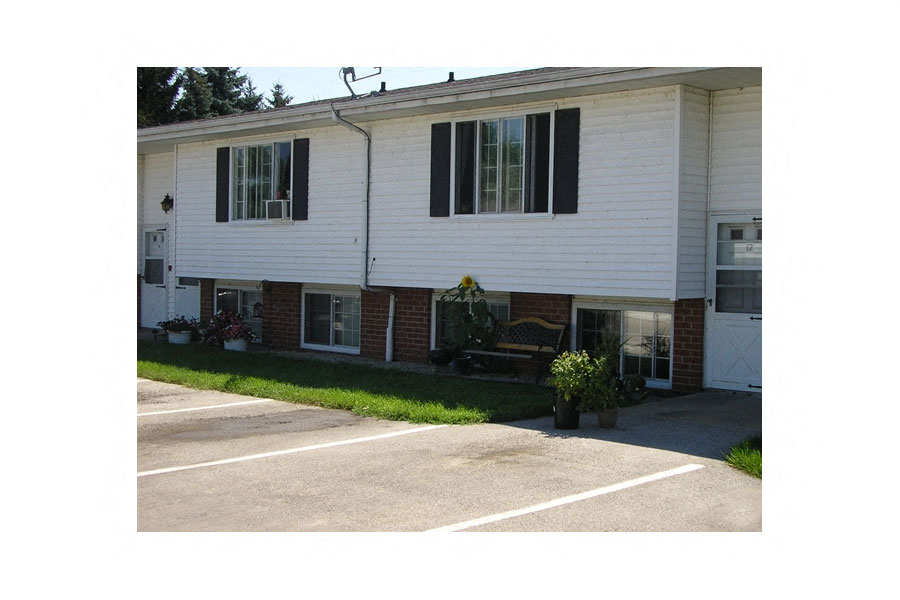 a white house with black shuttered windows and a driveway