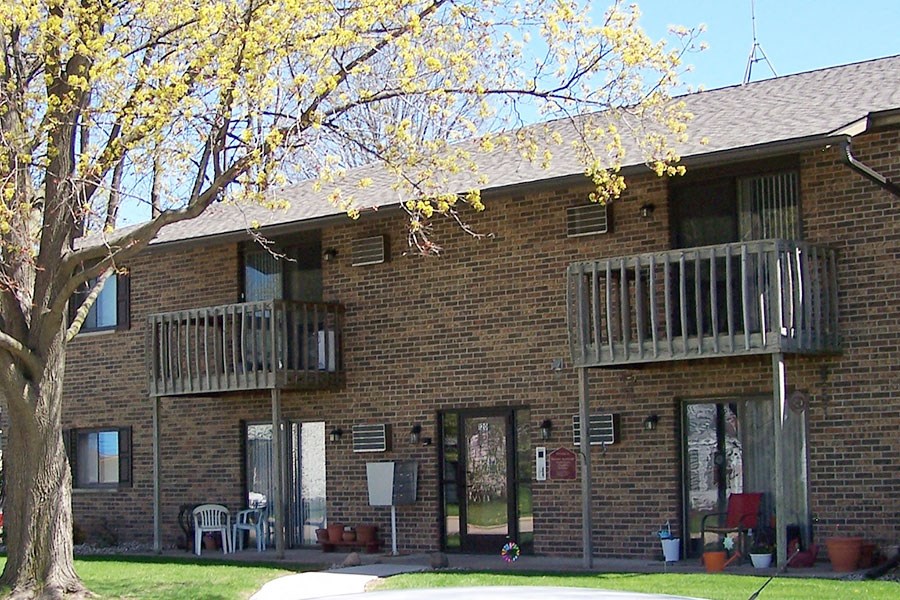 a brick building with two balconies and a tree