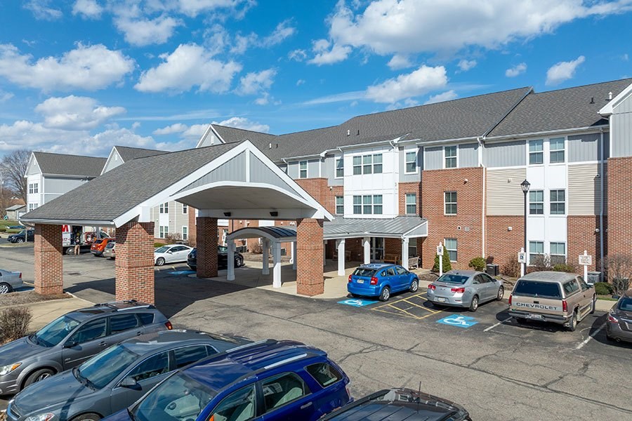A parking lot in front of a multi-story building with cars parked.