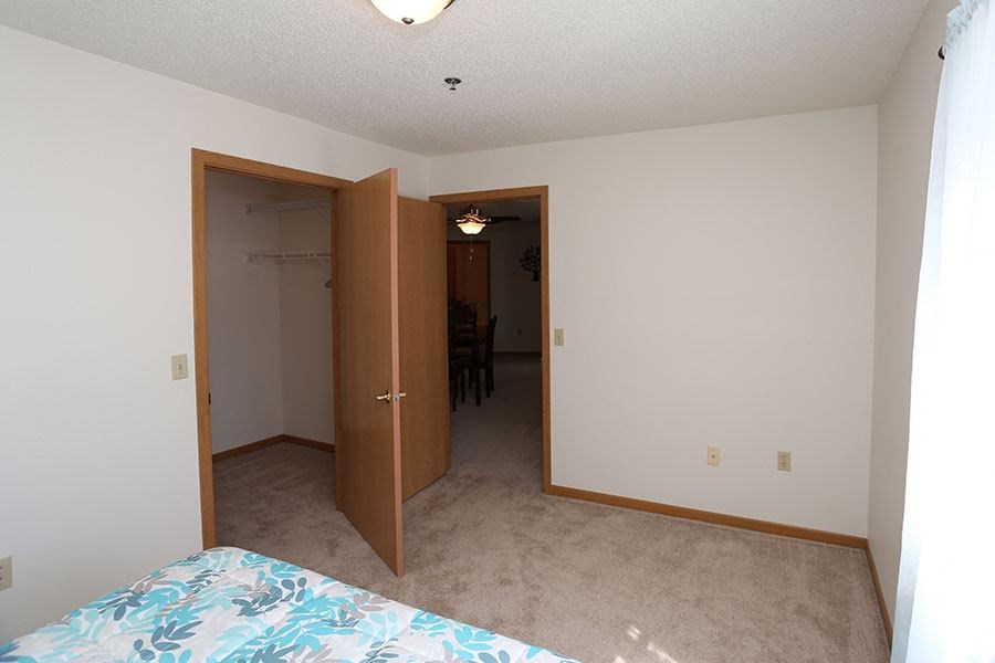 an empty bedroom with a bed and a closet