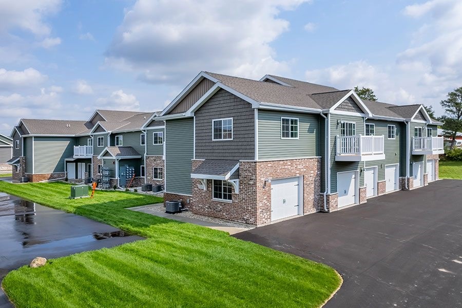 A row of houses with a paved driveway in front.