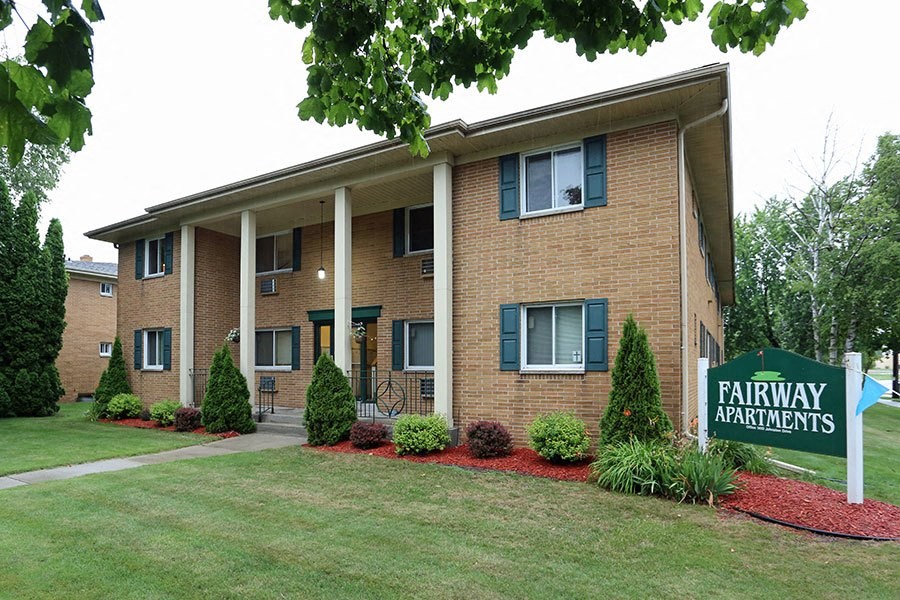 an apartment building with a yard and a sign for fairway apartments