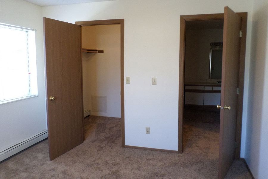 an empty room with two open doors and a closet