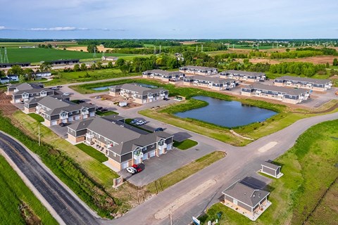an aerial view of a community with houses and a pond
